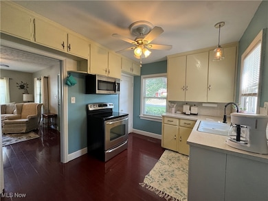 Kitchen with light countertops, appliances with stainless steel finishes, cream cabinetry, and hanging light fixtures