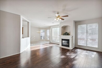 Unfurnished living room with ceiling fan with notable chandelier and dark hardwood / wood-style flooring