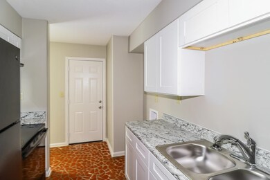Kitchen with black electric range oven, freestanding refrigerator, and white cabinets