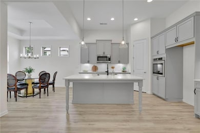 Kitchen with appliances with stainless steel finishes, gray cabinetry, recessed lighting, backsplash, and light countertops