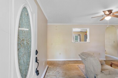 Entryway with arched walkways, a ceiling fan, and ornamental molding