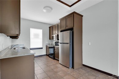 Kitchen with stainless steel appliances, a sink, light countertops, and baseboards