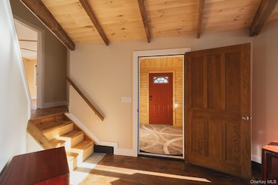 Entryway with dark wood-type flooring, a wood ceiling with exposed beams, and stairs