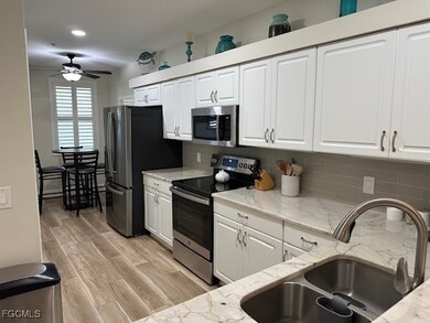 Kitchen with stainless steel appliances, white cabinetry, and light stone countertops