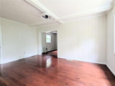Empty room with beamed ceiling, a textured ceiling, hardwood / wood-style flooring, and wood walls