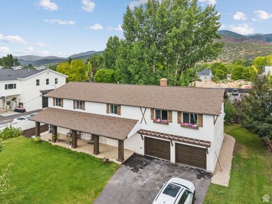 View of front of property featuring a mountain view, asphalt driveway, a front yard, a chimney, and a garage