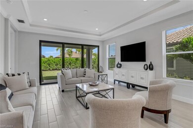 Living area featuring a raised ceiling, visible vents, baseboards, and plenty of natural light
