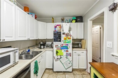 Kitchen featuring white appliances, a sink, white cabinets, light countertops, and ornamental molding