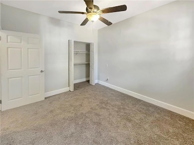 Unfurnished bedroom with ceiling fan and carpet fl