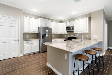 Another view of the beautifully updated kitchen showcasing crisp white cabinetry, sleek finishes, and abundant counter space for meal prep and entertaining (virtually staged).