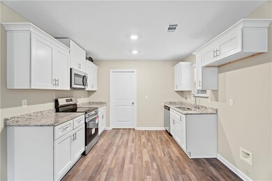 Kitchen featuring stainless steel appliances, a sink, light wood finished floors, baseboards, and recessed lighting