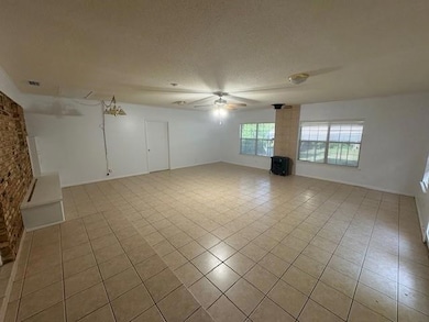 Unfurnished living room with light tile patterned floors, a ceiling fan, and a textured ceiling