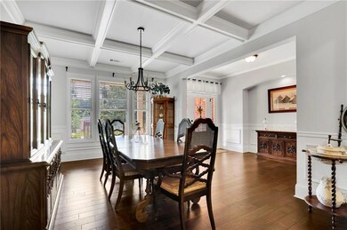 Dining space with healthy amount of natural light, beam ceiling, dark wood-style flooring, a chandelier, and wainscoting