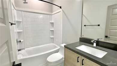 Guest bathroom featuring oversized vanity, tiled shower / bath combo, and toilet