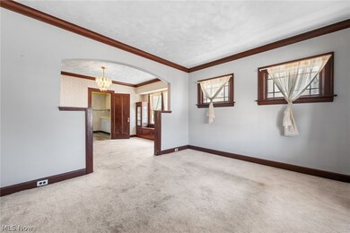 Living room with natural wood crown molding, carpet flooring over hardwood floors