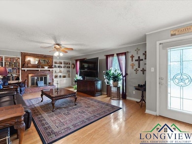 Living room featuring a textured ceiling, crown molding, ceiling fan, wood finished floors, and baseboards