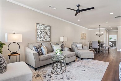 Living room featuring crown molding, ceiling fan w