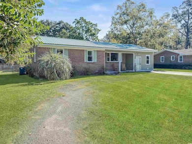 Single story home featuring a metal roof, brick siding, a front yard, and a porch