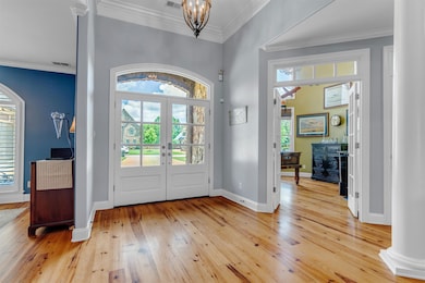 Entrance foyer with heart of pine wood floors, plenty of natural light, arched walkways, crown molding, and French doors.
