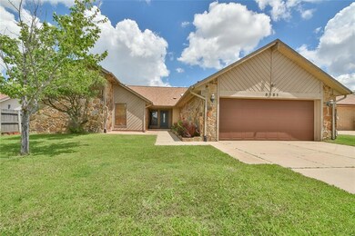 View of front of property featuring stone siding, an attached garage, and driveway