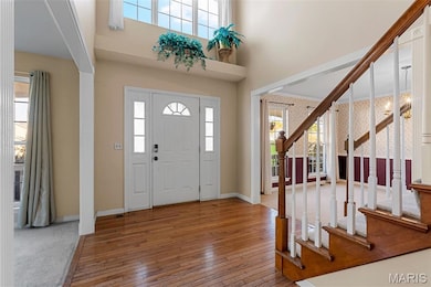 Entrance foyer with hardwood / wood-style flooring, stairway, and a high ceiling