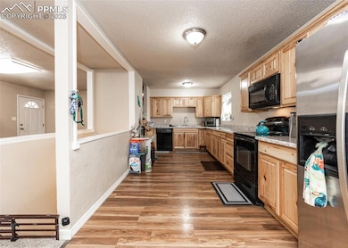 Kitchen featuring black appliances, light brown ca