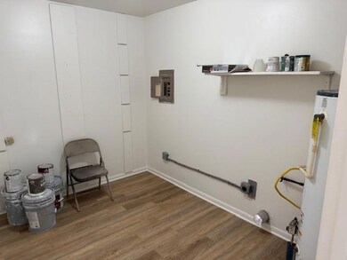 Laundry area featuring electric panel, baseboards,