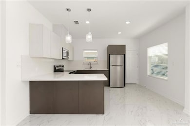 Kitchen featuring a peninsula, visible vents, appliances with stainless steel finishes, marble finish floor, and light countertops