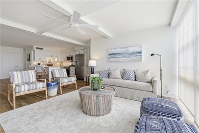 Living room featuring beam ceiling, wood finished floors, and ceiling fan