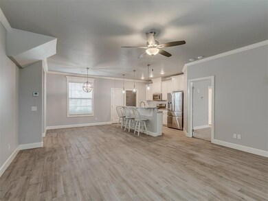 Kitchen with stainless steel appliances, crown molding, a kitchen breakfast bar, ceiling fan, and baseboards