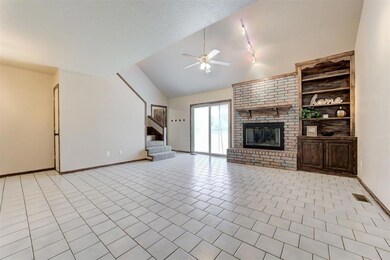 Unfurnished living room with a ceiling fan, lofted ceiling, stairs, a fireplace, and light tile patterned flooring