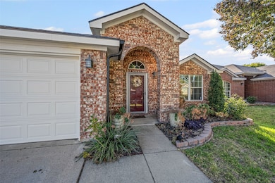 View of exterior entry featuring brick siding and a yard