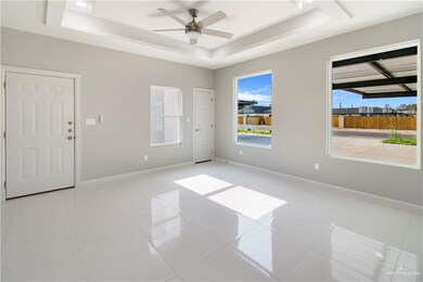 Empty room with a raised ceiling, ceiling fan, baseboards, and light tile patterned floors