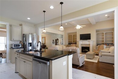 Kitchen with stainless steel appliances, dark countertops, a fireplace, beamed ceiling, and ceiling fan
