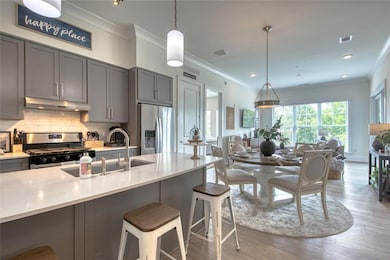Kitchen with pendant lighting, gray cabinets, light stone countertops, and stainless steel appliances
