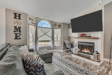 Living area featuring wood finished floors, a glass covered fireplace, and lofted ceiling