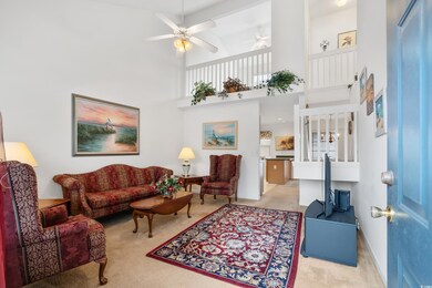 Living room with ceiling fan, a towering ceiling, 