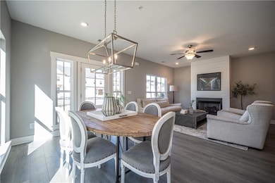 Dining space with a chandelier, dark wood-type flooring, a fireplace, recessed lighting, and a ceiling fan