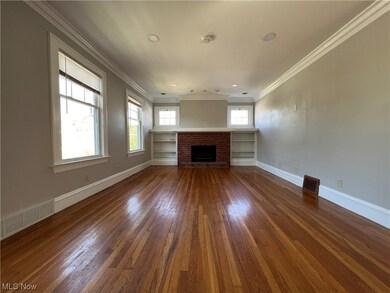 Unfurnished living room featuring dark wood-type flooring, a brick fireplace, and crown molding