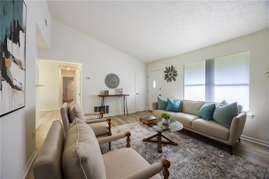 Living area with light wood-style floors and high vaulted ceiling