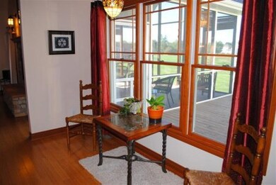 The breakfsat room has continuous hardwoood floors, venetian glass light fixture, Andersen architectural series windows with a glimpse of the sun deck and screened porch.