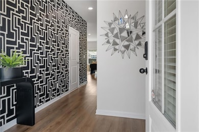 Wine cellar featuring wood finished floors, recessed lighting, and wallpapered walls