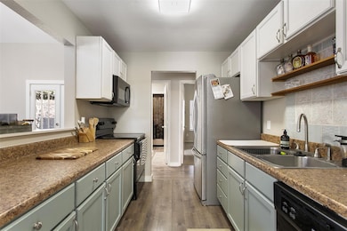 Kitchen featuring white cabinets, dark hardwood / wood-style flooring, sink, and black appliances