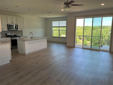 Kitchen with appliances with stainless steel finishes, white cabinets, recessed lighting, open floor plan, and light wood-style flooring