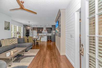Living room featuring a textured ceiling, wood finished floors, a ceiling fan, a chandelier, and recessed lighting