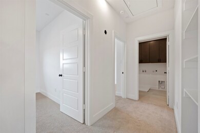 Hall with light colored carpet and attic access
