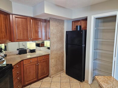 Kitchen with a textured ceiling, brown cabinets, a