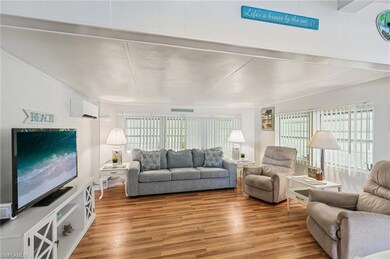 Living room featuring plenty of natural light, wood finished floors, and a wall unit AC