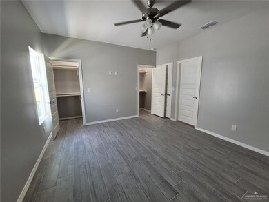 Unfurnished bedroom with baseboards, visible vents, a walk in closet, and dark wood finished floors