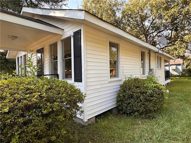 View of side of home featuring covered porch and a lawn
